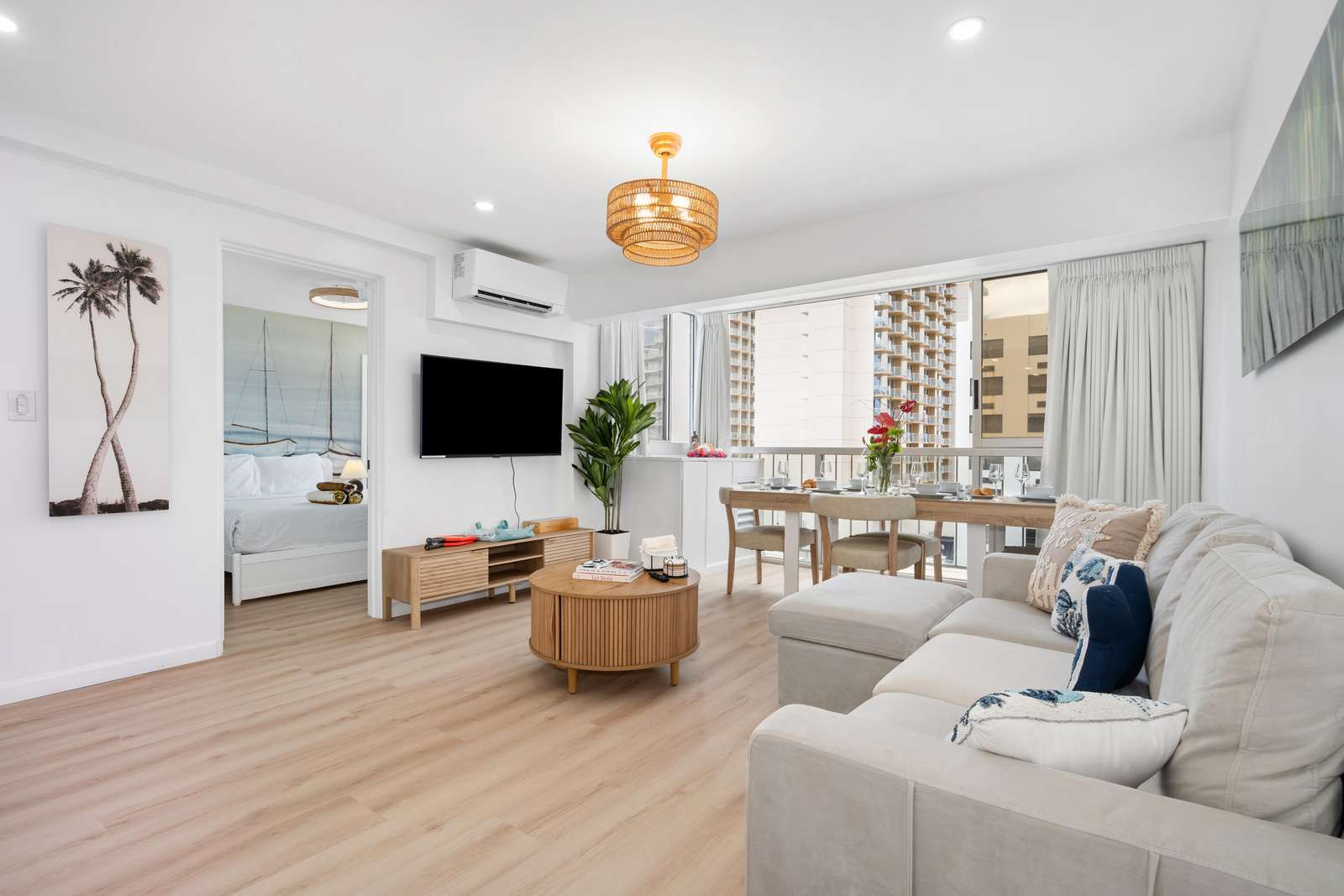 A round wood coffee table sits before a light beige sectional accented with blue and patterned pillows.