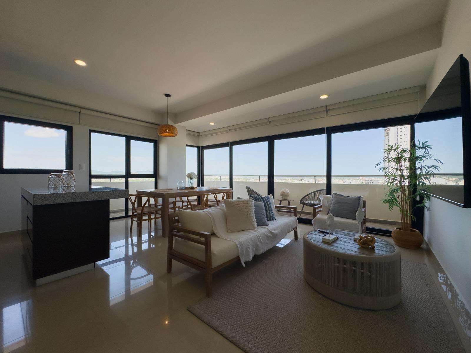 Living area with white cushioned wood sofa, round wood coffee table, and wall-mounted flat screen TV. - property