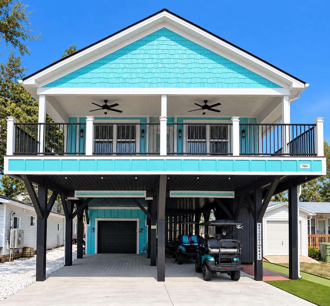 Turquoise siding with black lattice ceiling contrasts the concrete driveway and garage beneath the elevated porch. - property
