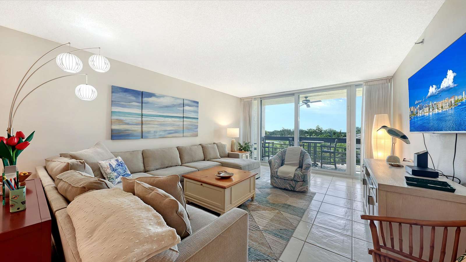 Living room with beige sectional, patterned armchair, wood coffee table, and sliding glass doors opening to balcony.