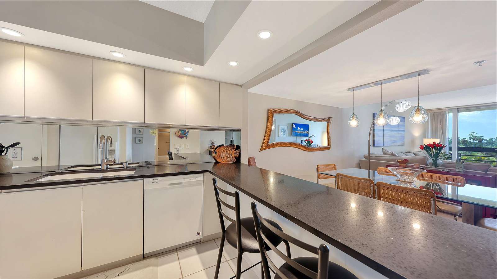 Black granite countertop with three bar stools overlooks dining area and living room with balcony view.