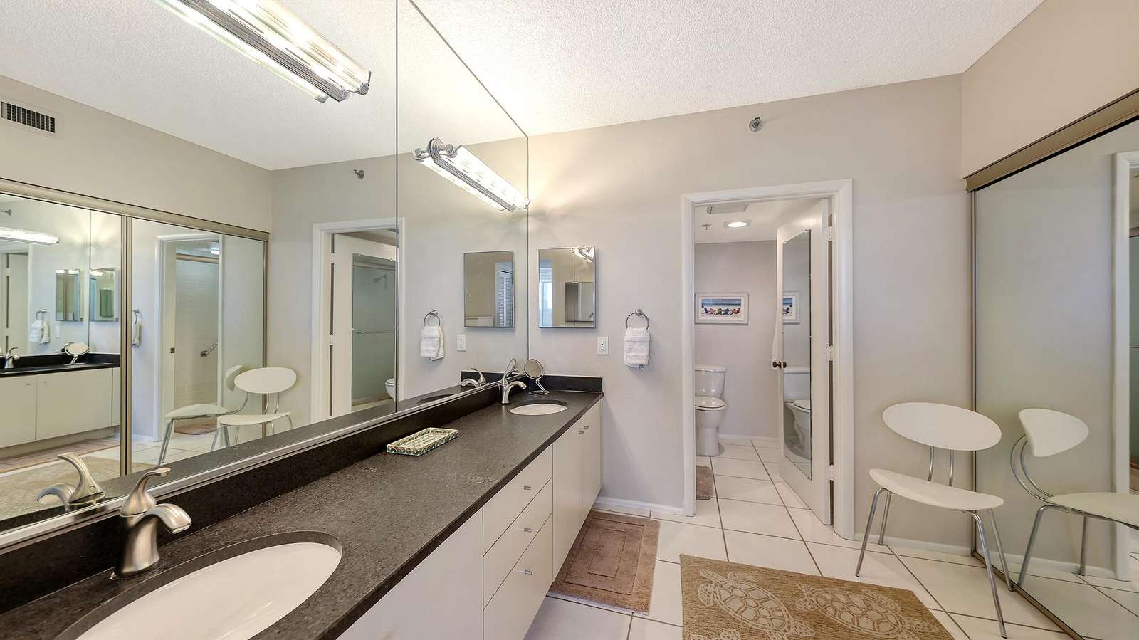 Bathroom vanity with black granite countertop, dual sinks, and large wall mirror reflecting the room.