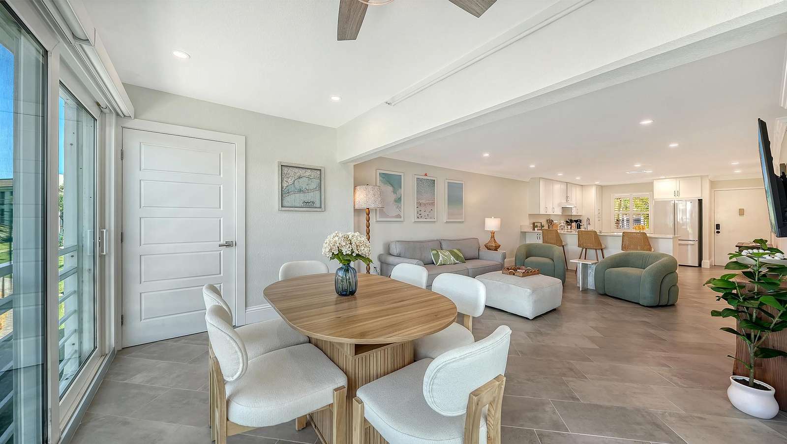 Light gray tile flooring flows through the open living and dining area with a round wood table and plush white chairs.