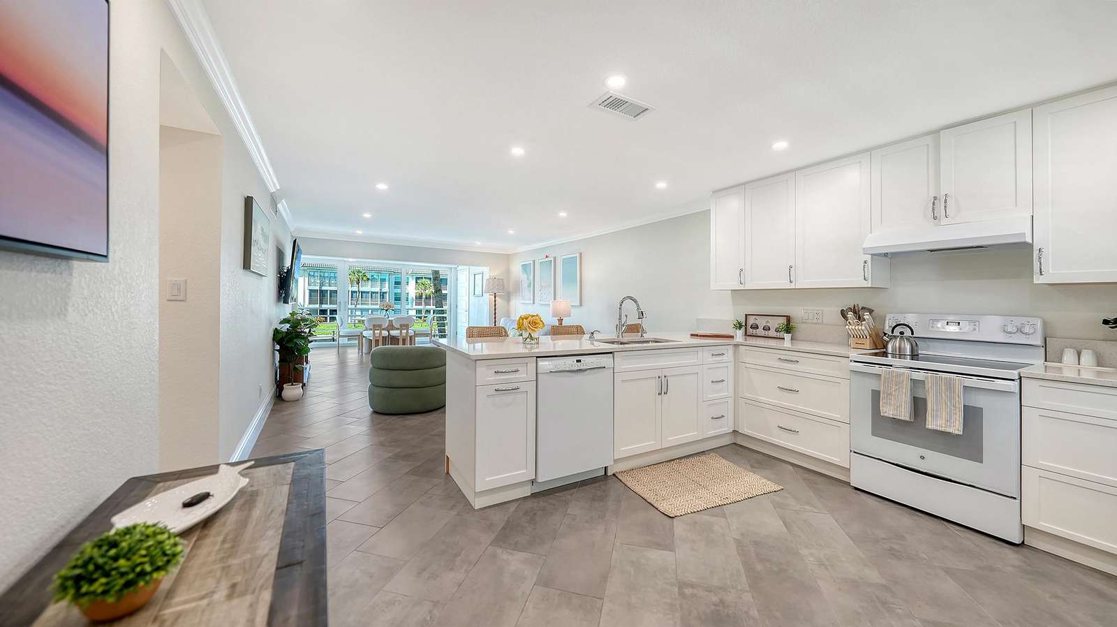 Open kitchen with white cabinetry, quartz countertops, and a central island overlooking the living area.