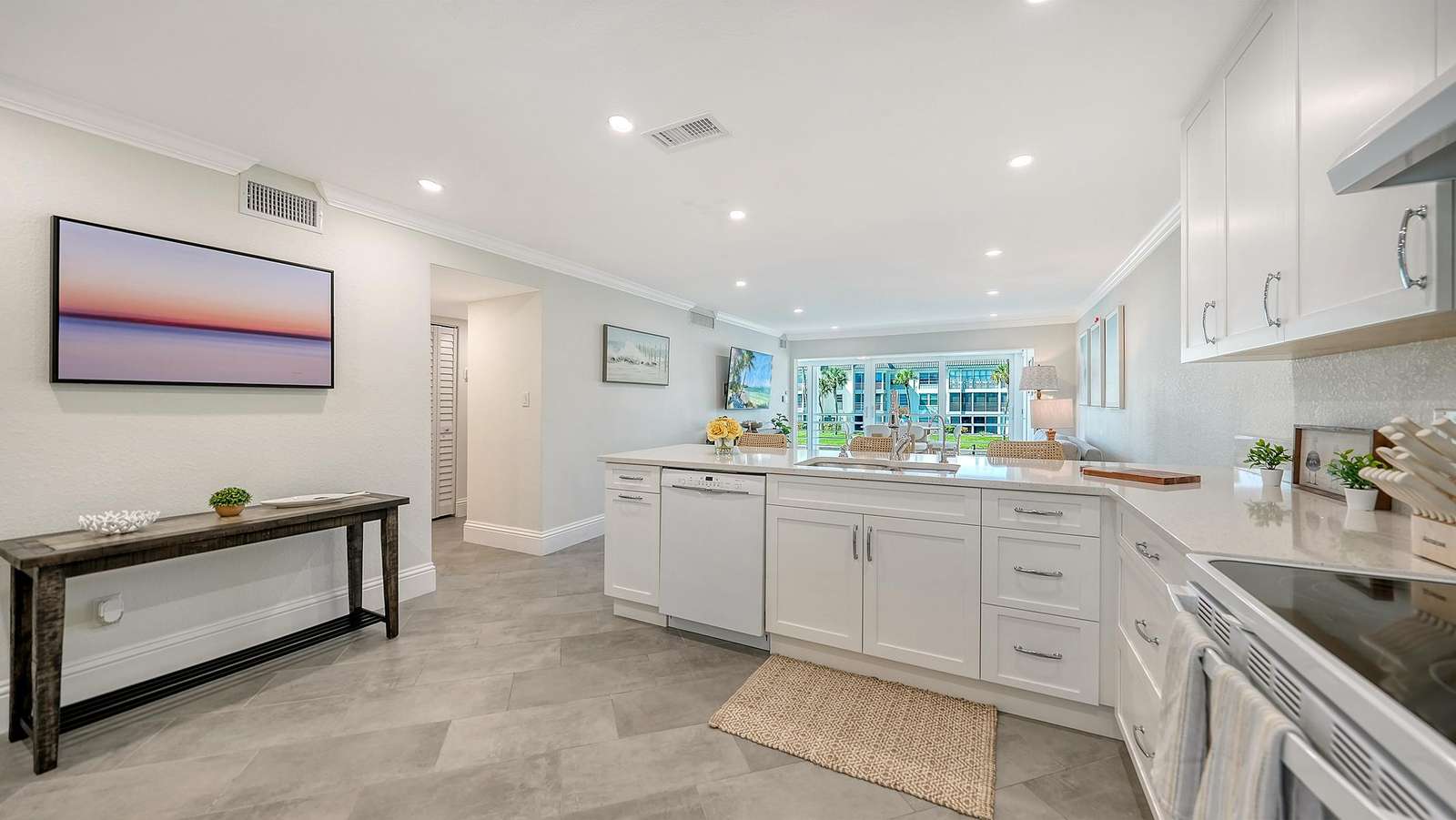 Open-concept kitchen with white cabinetry, quartz countertops, stainless appliances, and gray tile flooring.