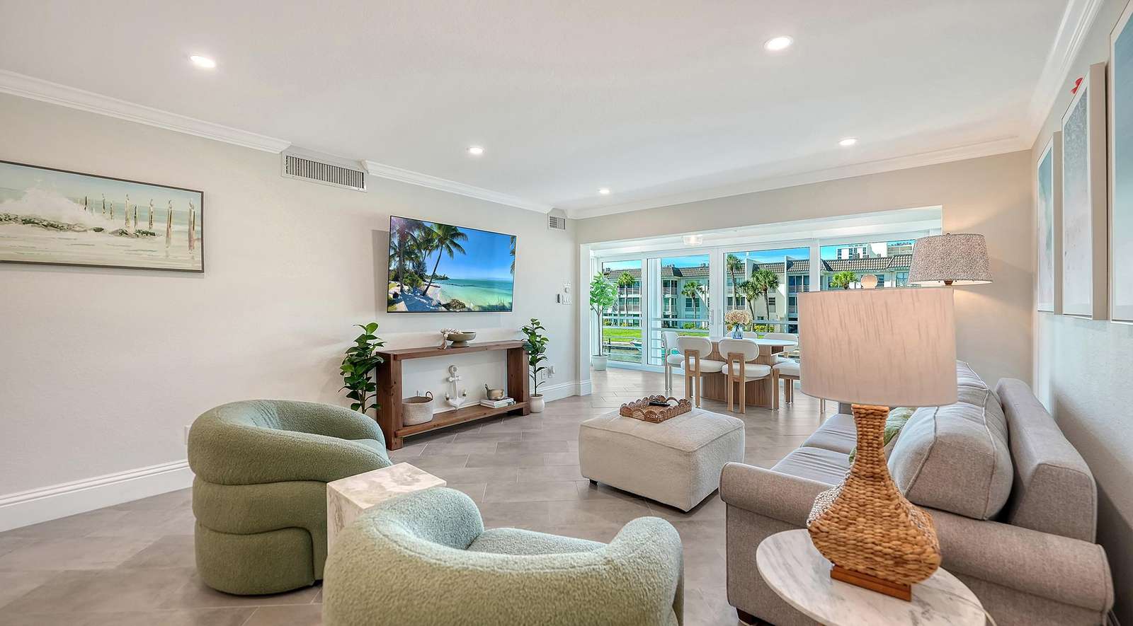 Living room with textured sage armchairs, light gray sofa, marble side table, and wall-mounted flat-screen TV.