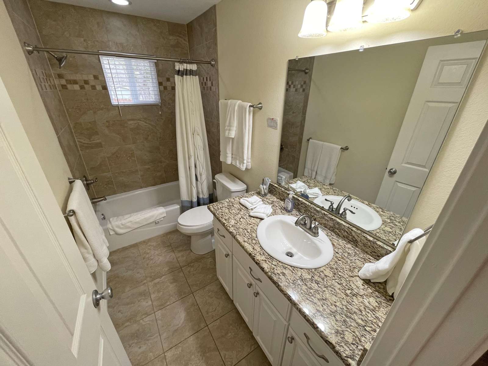 The main bathroom with granite counters and tile shower/tub unit.