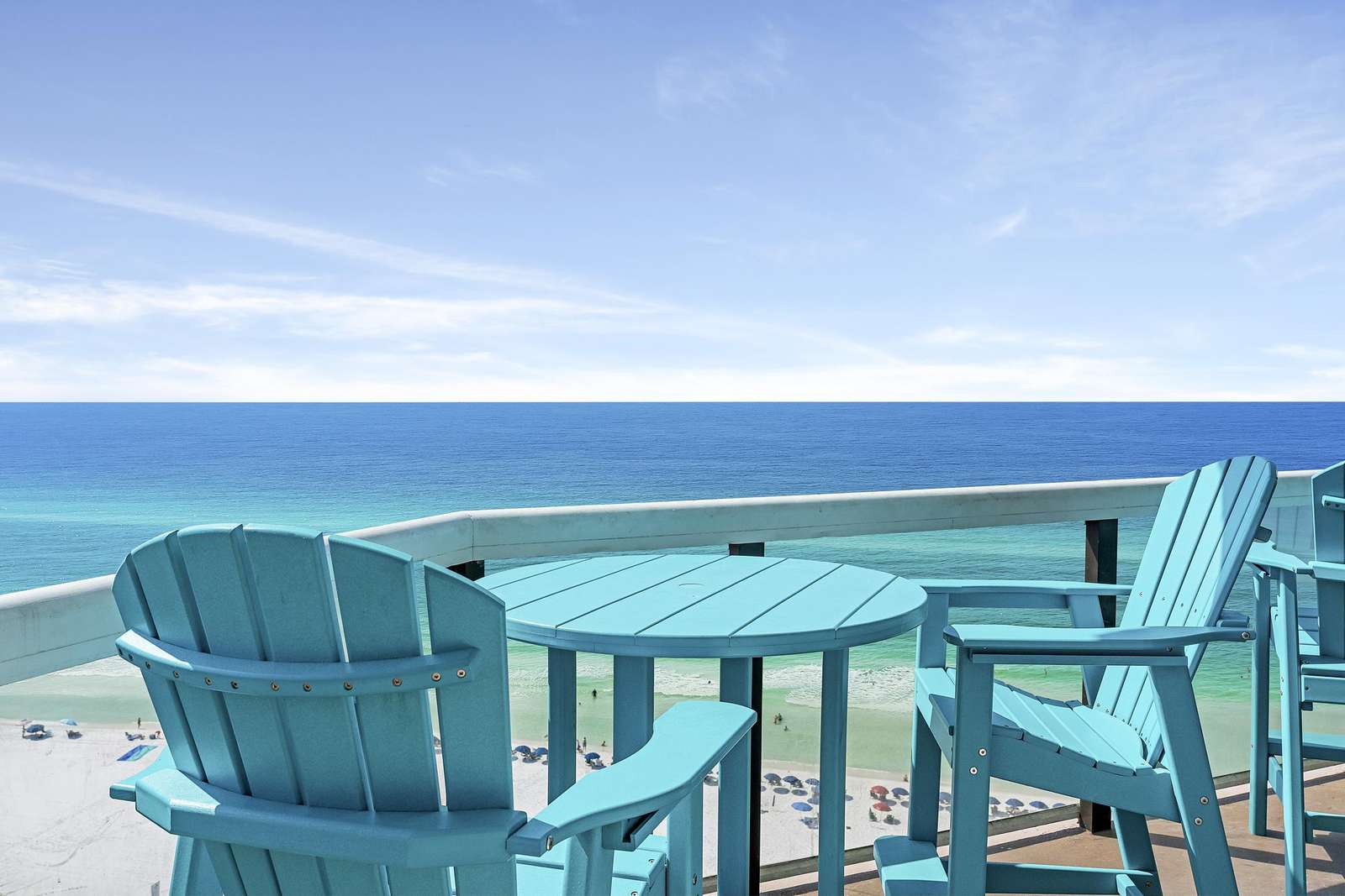 Balcony with turquoise Adirondack chairs and round table overlooks emerald Gulf waters and sandy beach below. - property