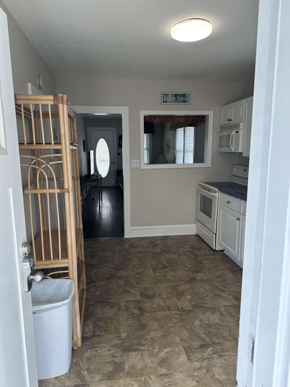 Entryway view into kitchen with white cabinetry, electric stove, microwave, and beige vinyl flooring.