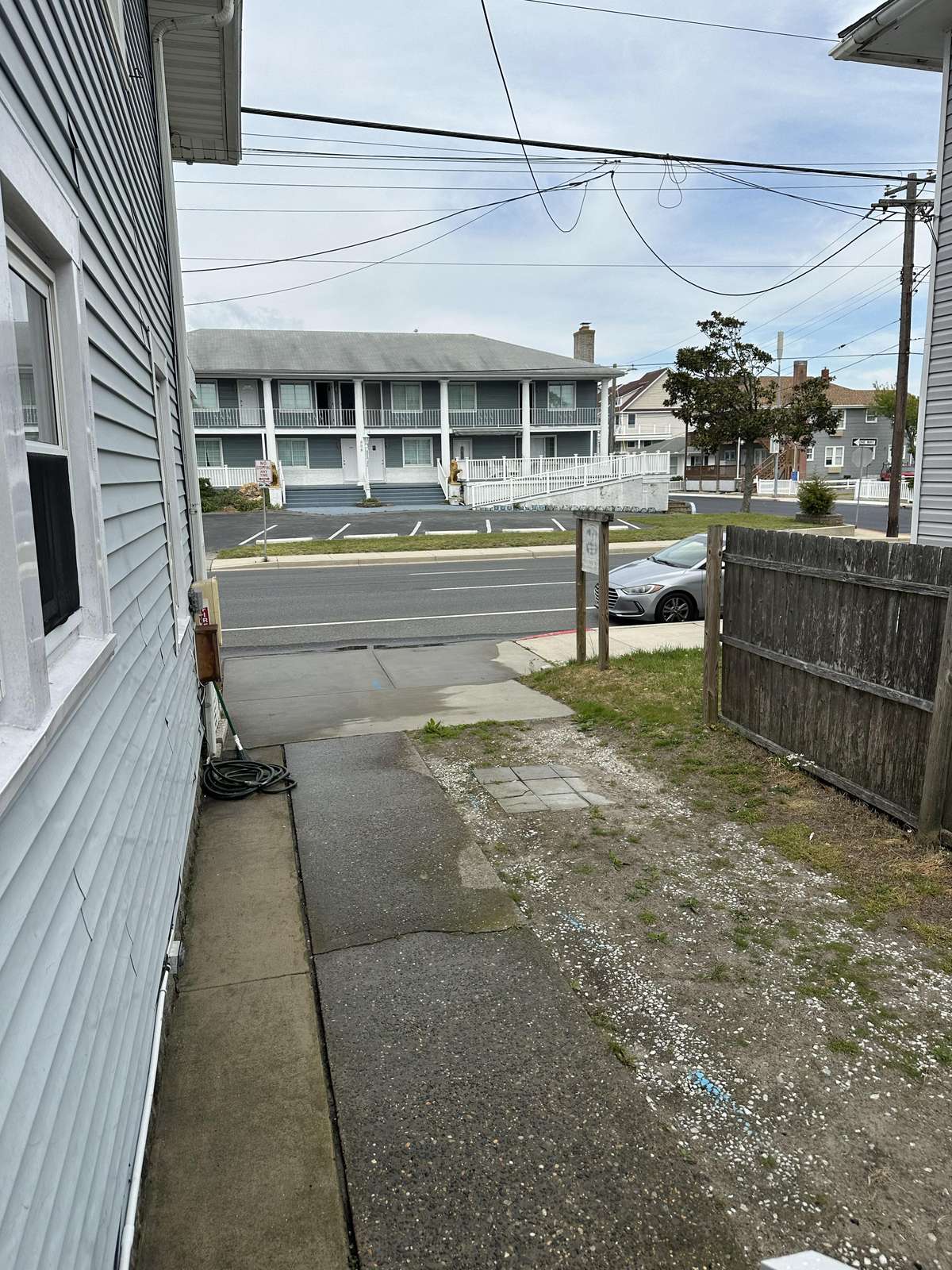 Narrow side yard with concrete and gravel path, adjacent to blue siding and wooden fence.