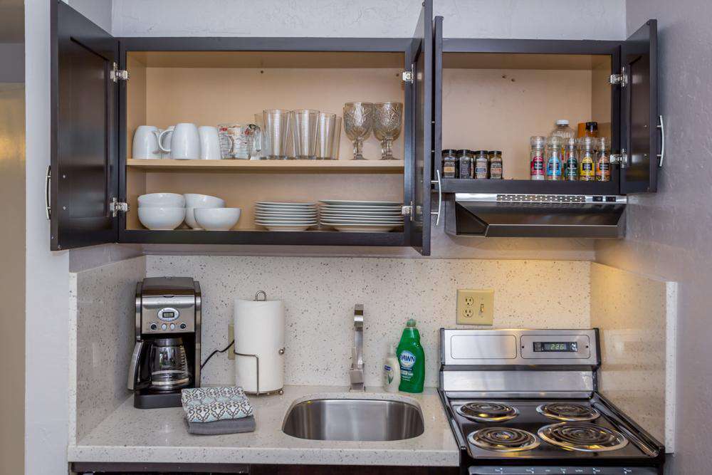 Cupboards are stocked with dishes, pots and pans, utensils, spices and cooking oils.
