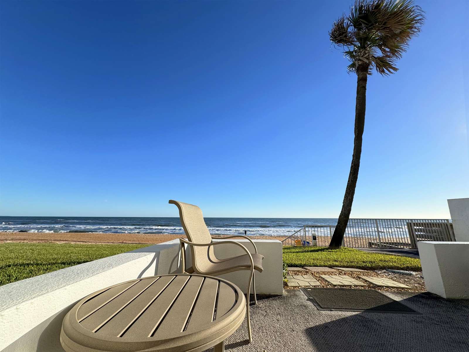 Oceanfront patio with stunning beach and palm tree views - property