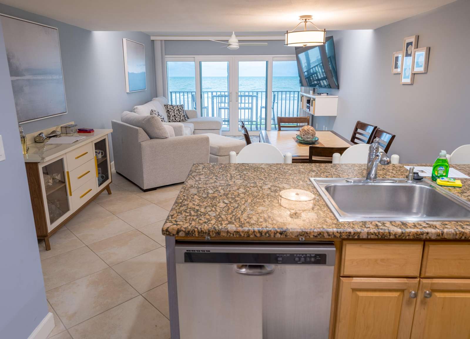 Kitchen island with granite countertop and stainless steel sink opens to living and dining areas with ocean views. - property
