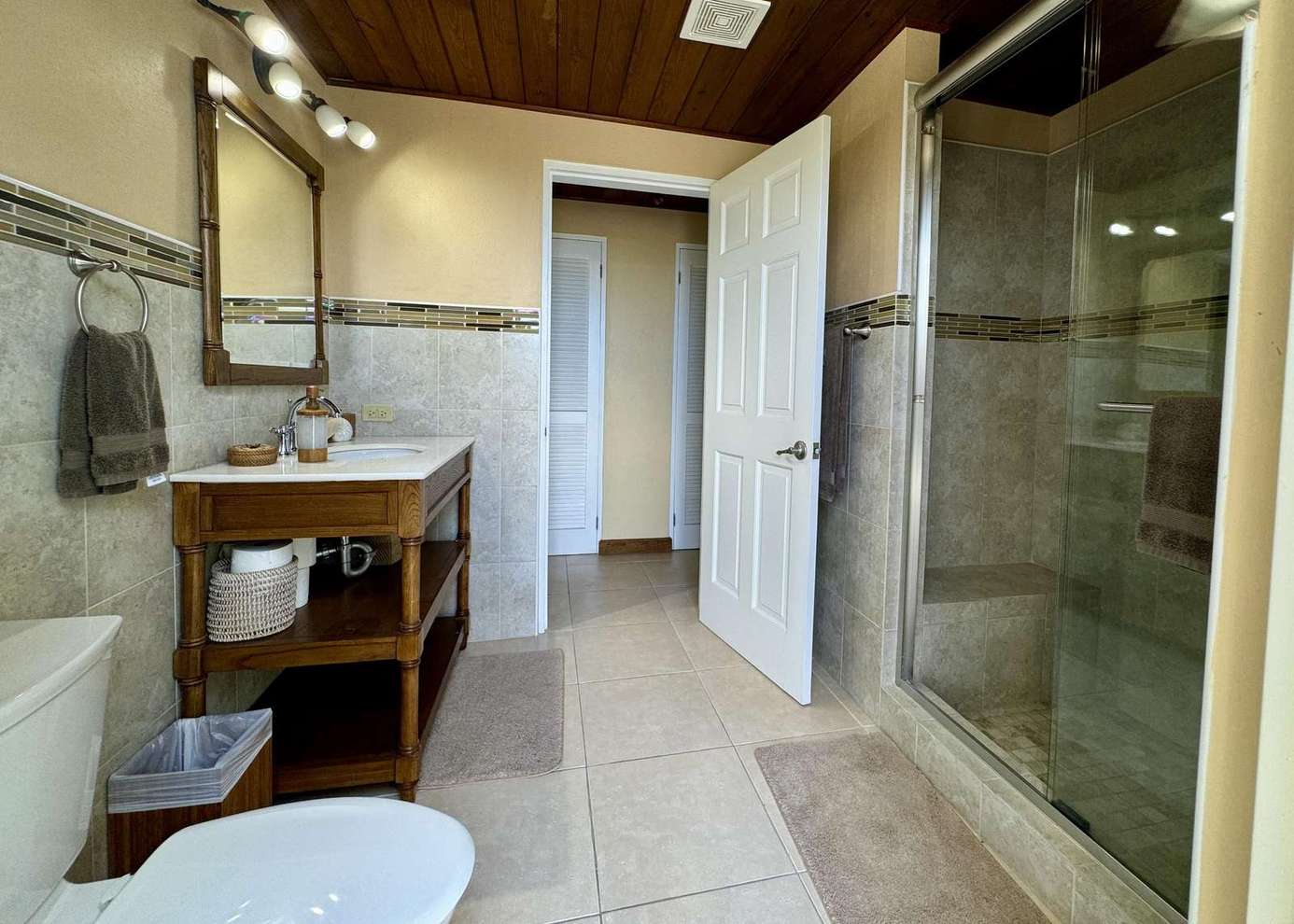 Spacious bathroom with modern glass shower and warm wood accents