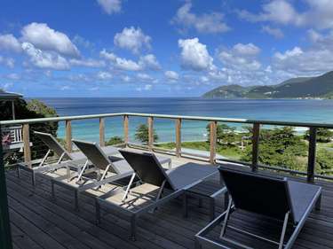 Oceanfront deck with panoramic views and lounge chairs