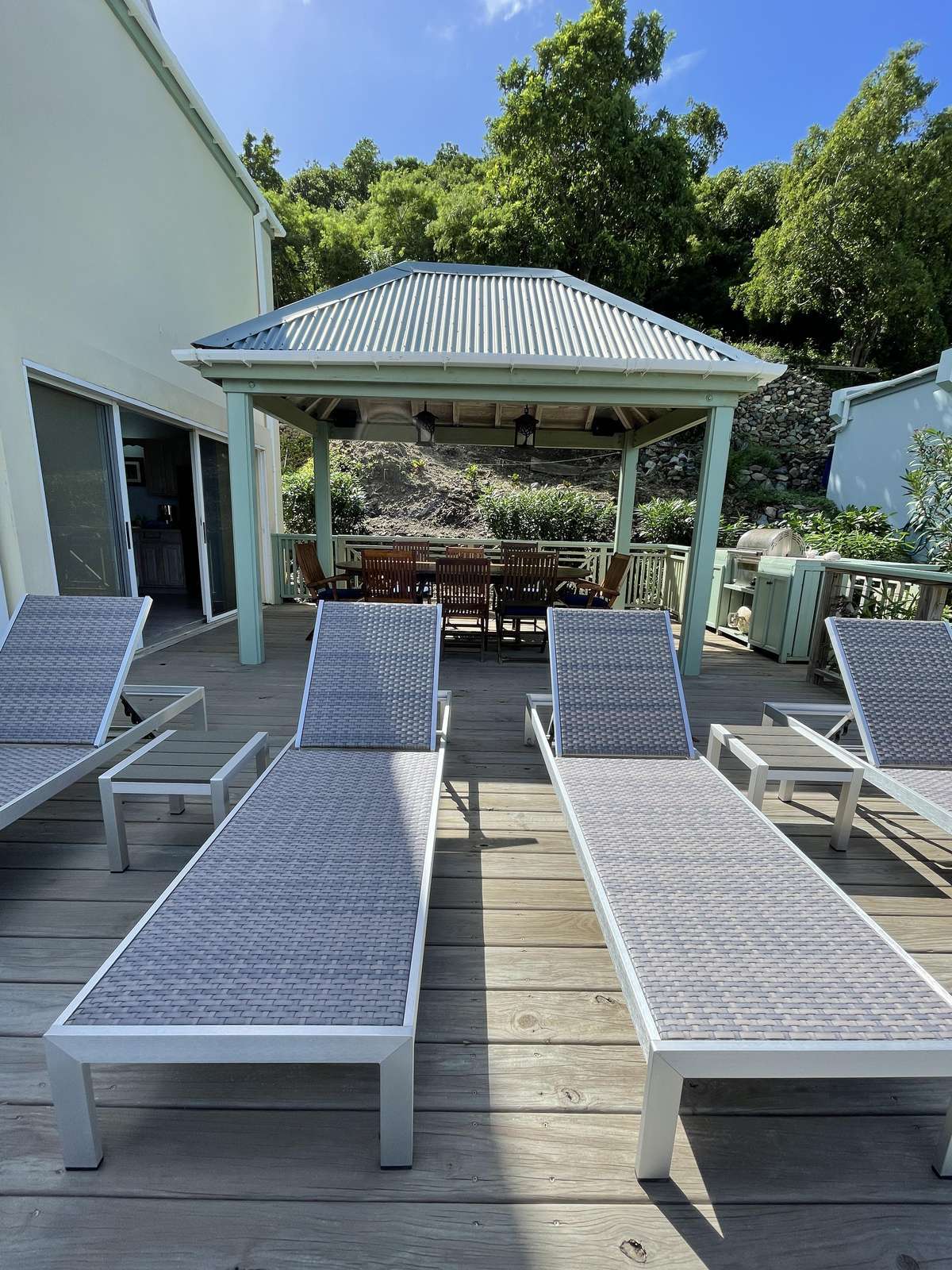 Sun-drenched patio with loungers and shaded dining area