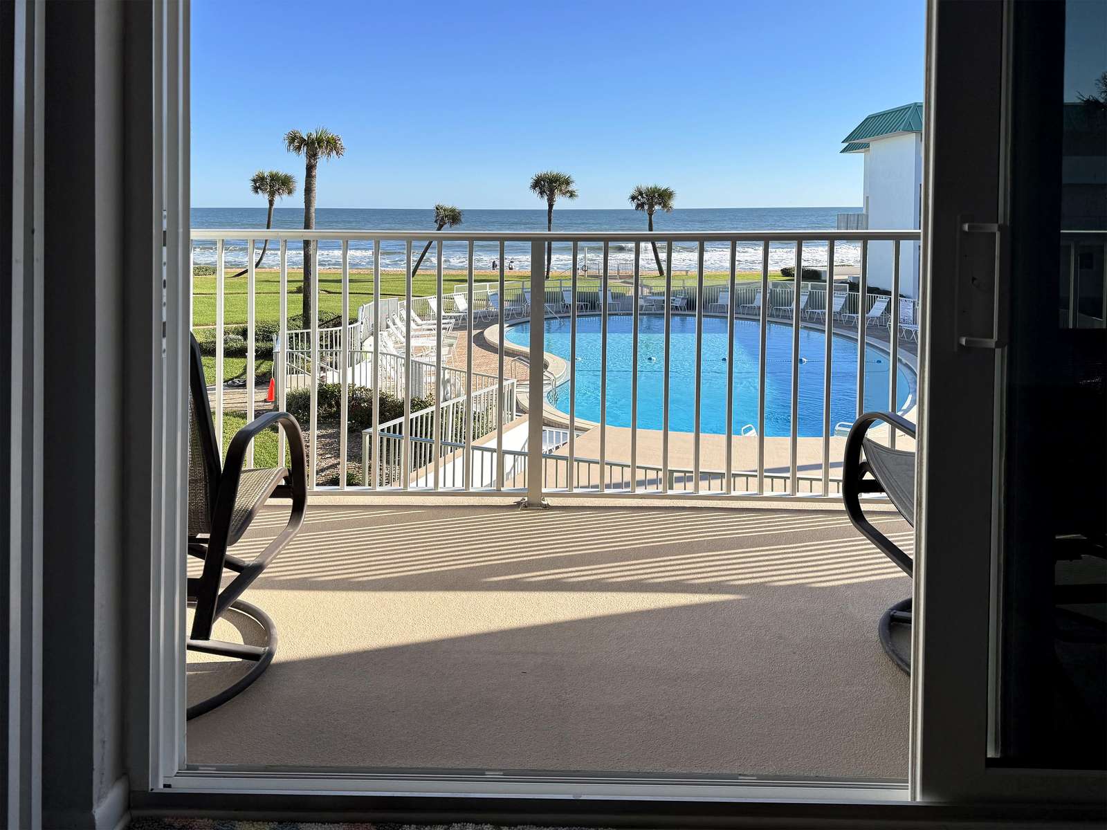 Balcony view overlooking sparkling pool and palm trees - property