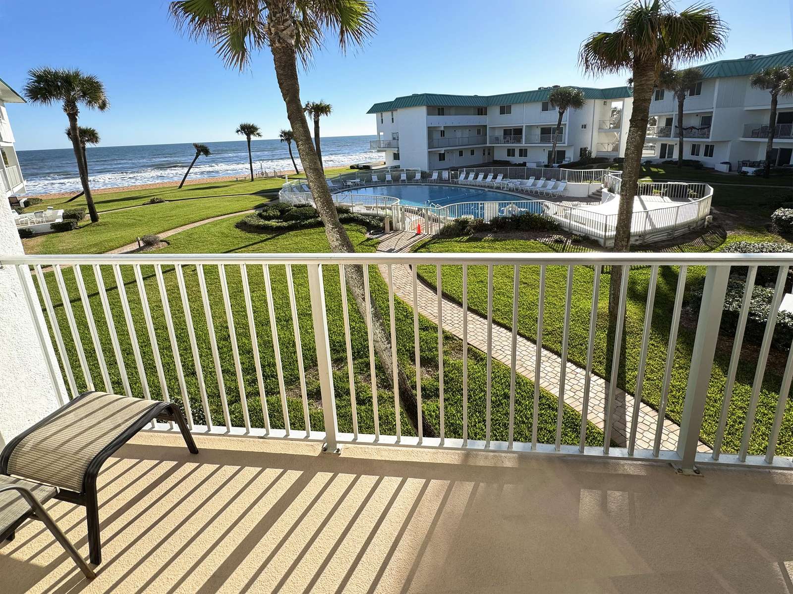 Oceanfront balcony with stunning pool and palm views - property