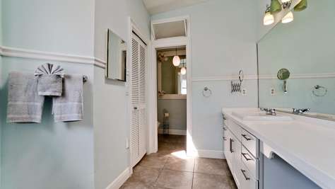 Bathroom features a long white vanity with multiple drawers, a large mirror, and soft blue walls.