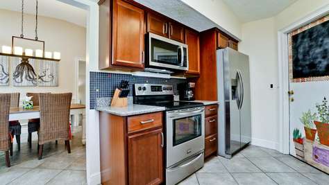 Kitchen features stainless steel appliances, dark wood cabinets, granite counters, and a mosaic tile backsplash.