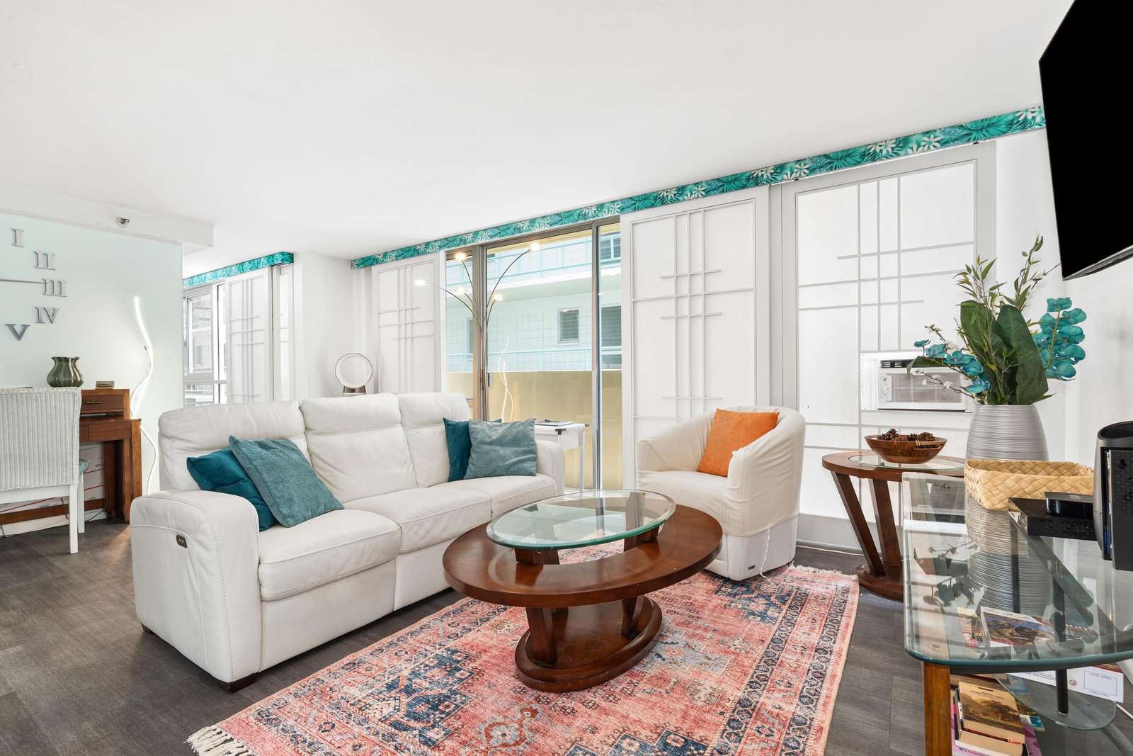 Light filters through sliding doors with frosted panels framing the white leather sofa and round wooden coffee table.