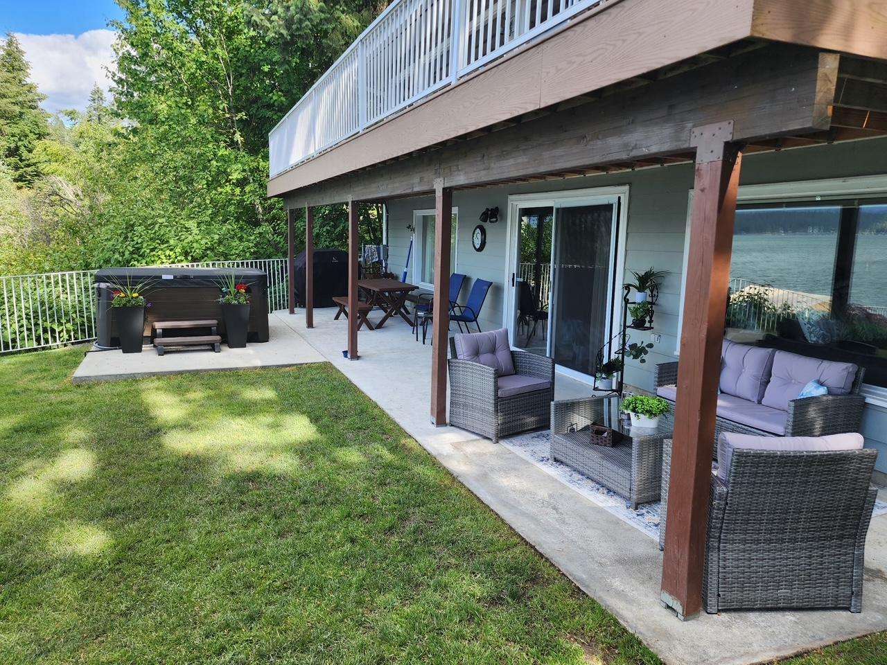 Patio seating with cushioned wicker furniture and glass coffee table overlooks lake through large sliding door.