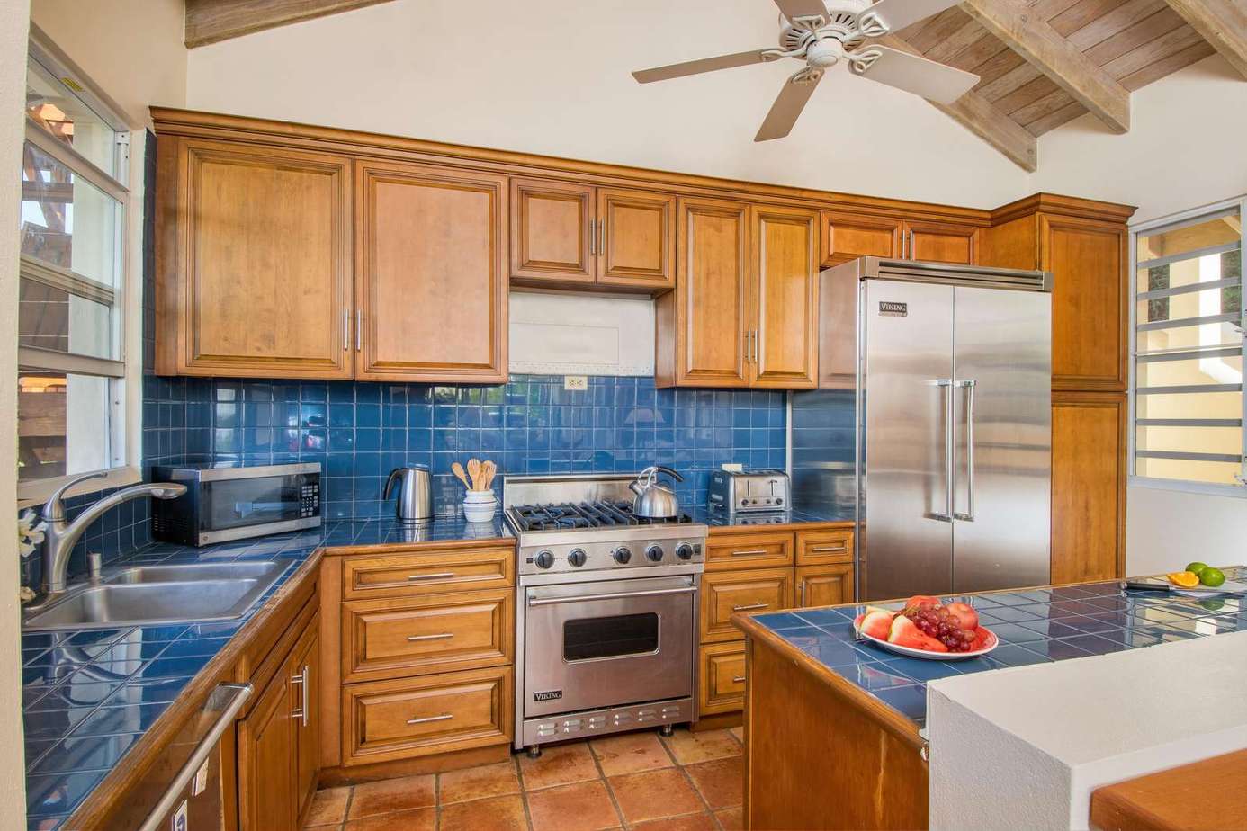 Spacious kitchen with vibrant blue tile and stainless steel appliances