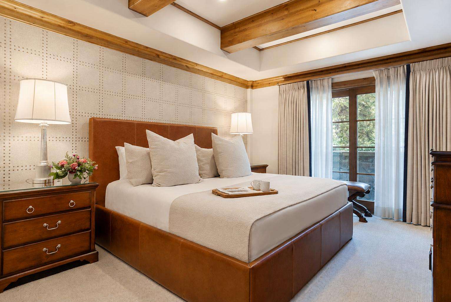A wide-angle view of a hotel room with a large bed, two nightstands, and a window