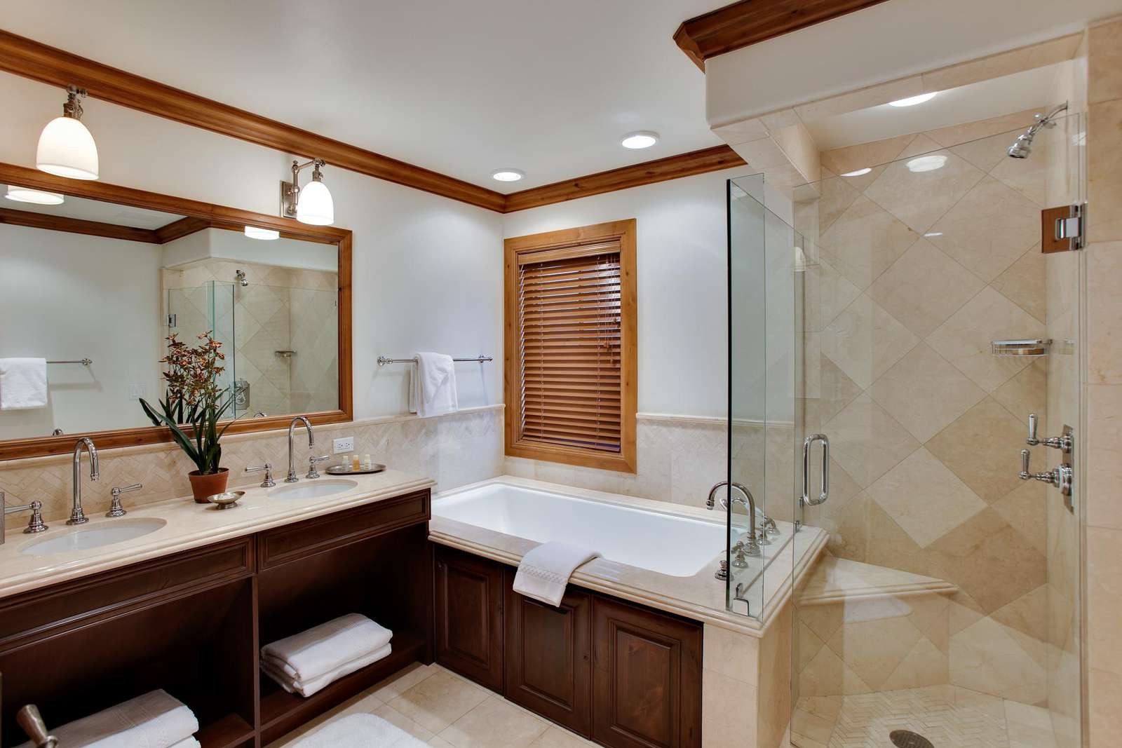 A luxurious bathroom with a double vanity, jacuzzi tub, and glass-enclosed shower.