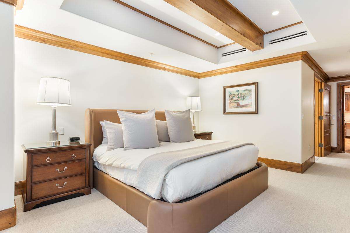 A wide view of a hotel room with a bed, nightstands, and a picture frame on the wall.
