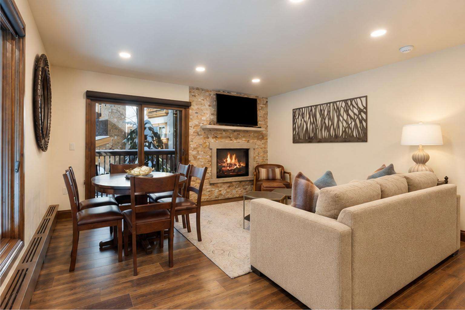 A living room with a fireplace, sofa, dining table, and TV.