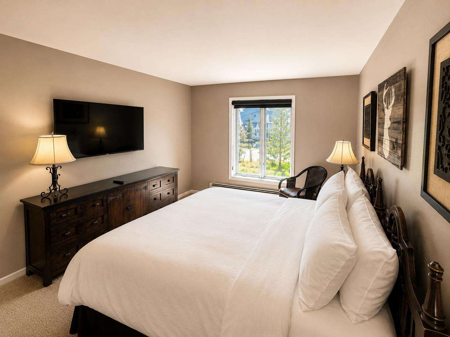 A wide-angle view of a hotel room with a large bed, dresser, TV, and window.