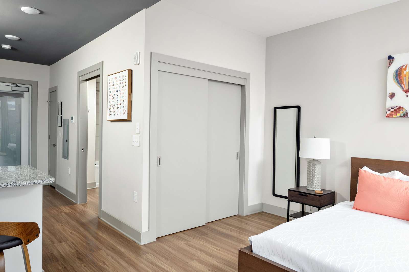 A wide view of a modern hotel room with a bed, nightstand, and mirror.