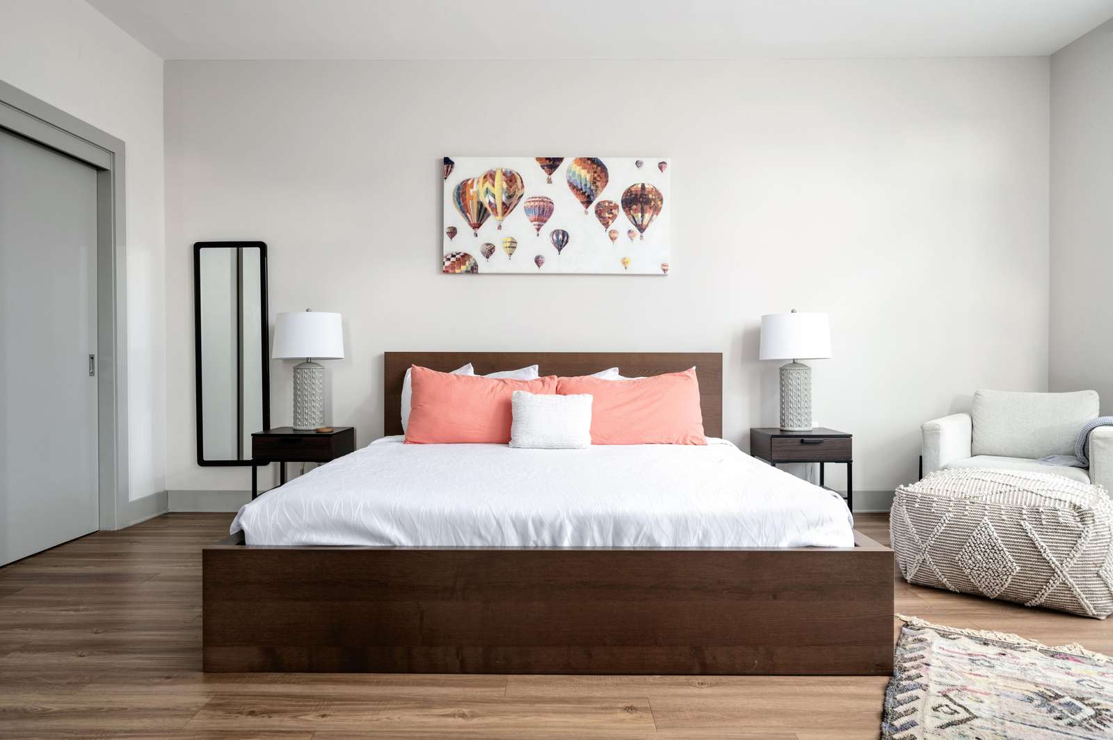 A wide view of a hotel room with a large bed, two nightstands, a chair, and a rug.