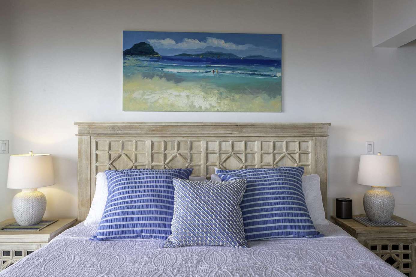 Cozy bedroom retreat with serene coastal artwork and soft lighting