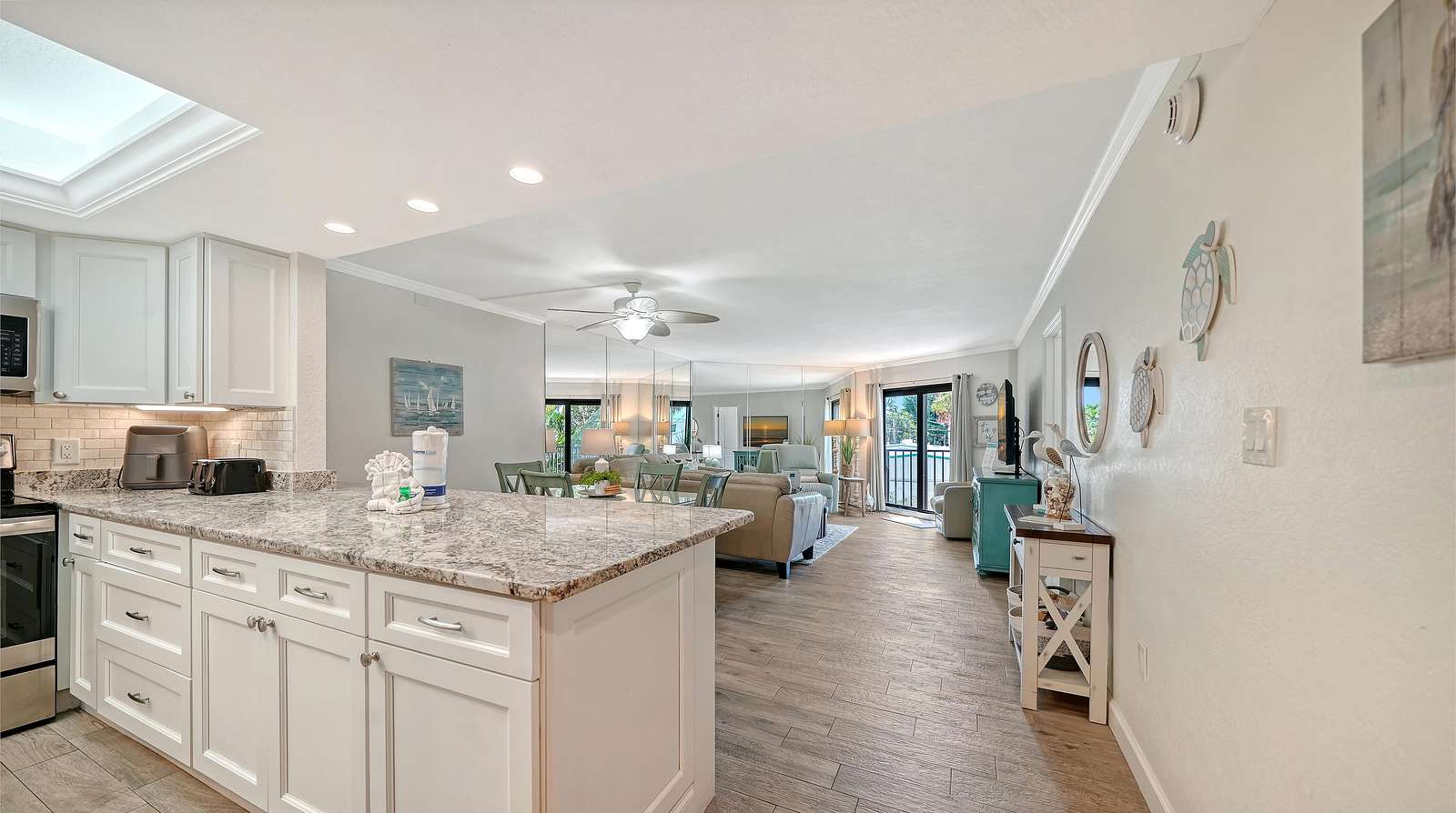 Granite countertop extends into the open kitchen with white cabinetry, overlooking the living and dining area. - property