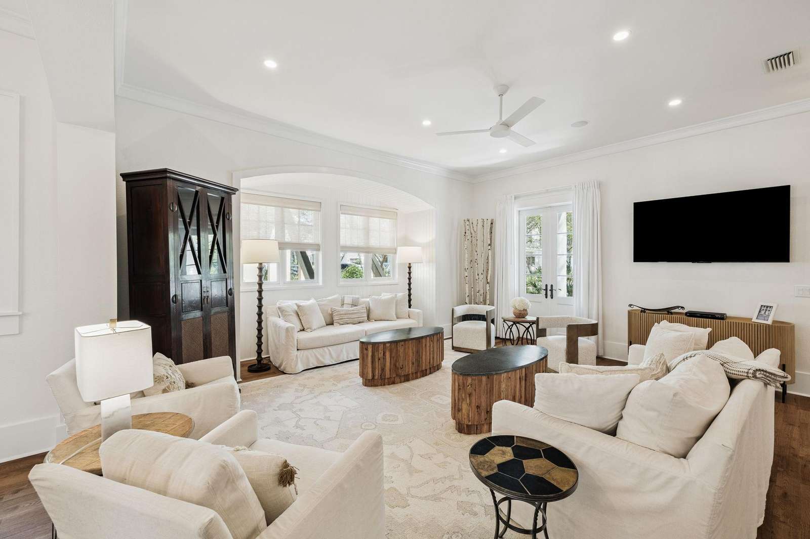 Neutral-toned seating surrounds two oval wood coffee tables beneath recessed lighting and a ceiling fan. - property
