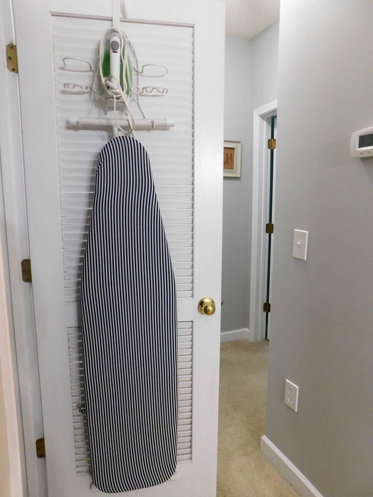 iron/iron board hanging in closet next to washer/dryer