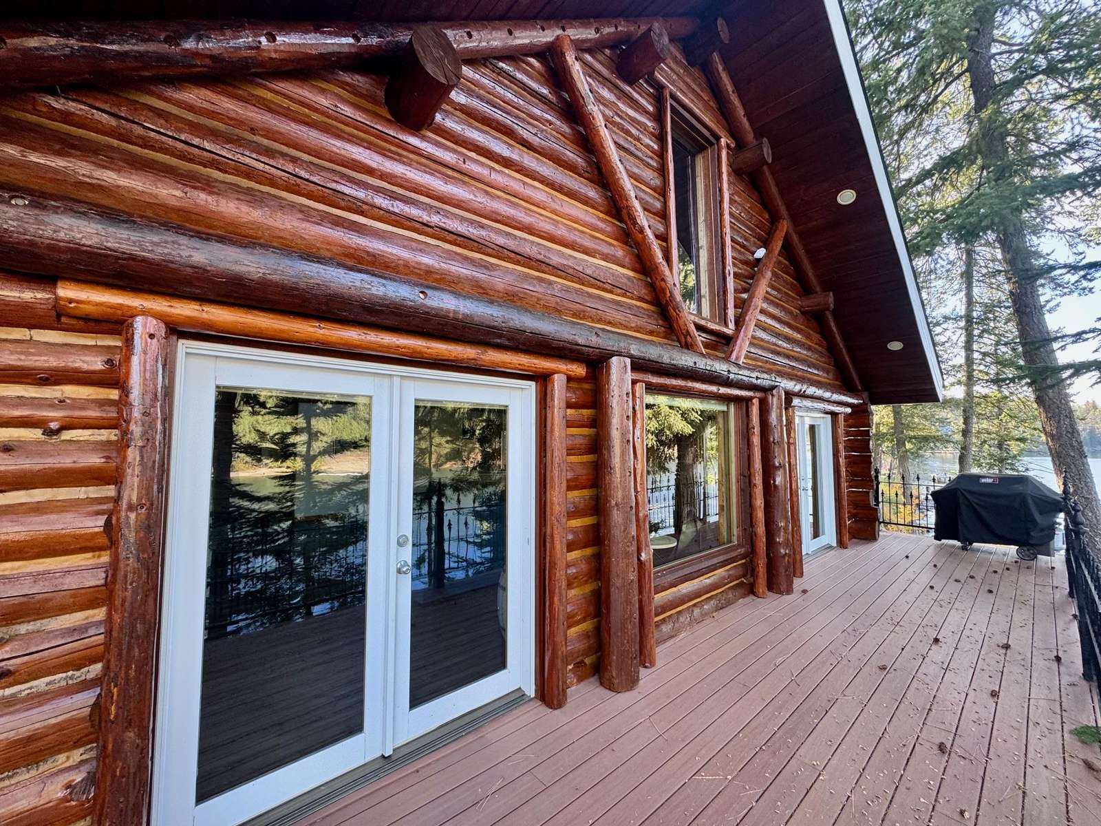 Spacious log cabin deck with forest views and grill