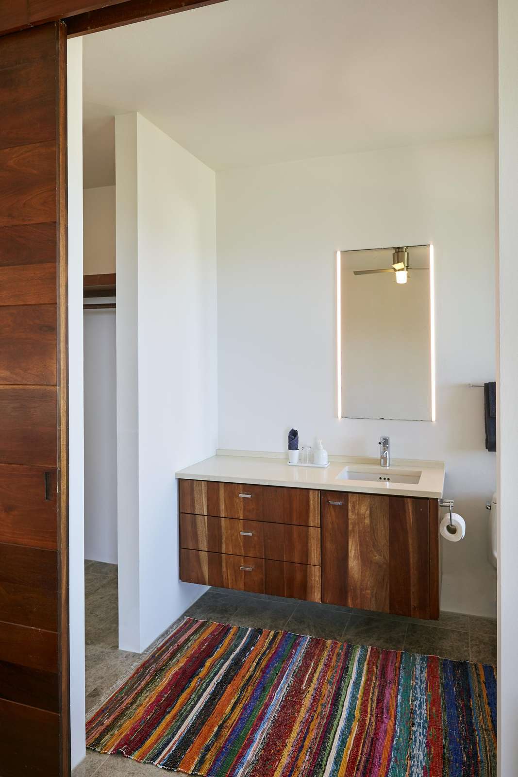 Bright bathroom with modern wood vanity and colorful rug