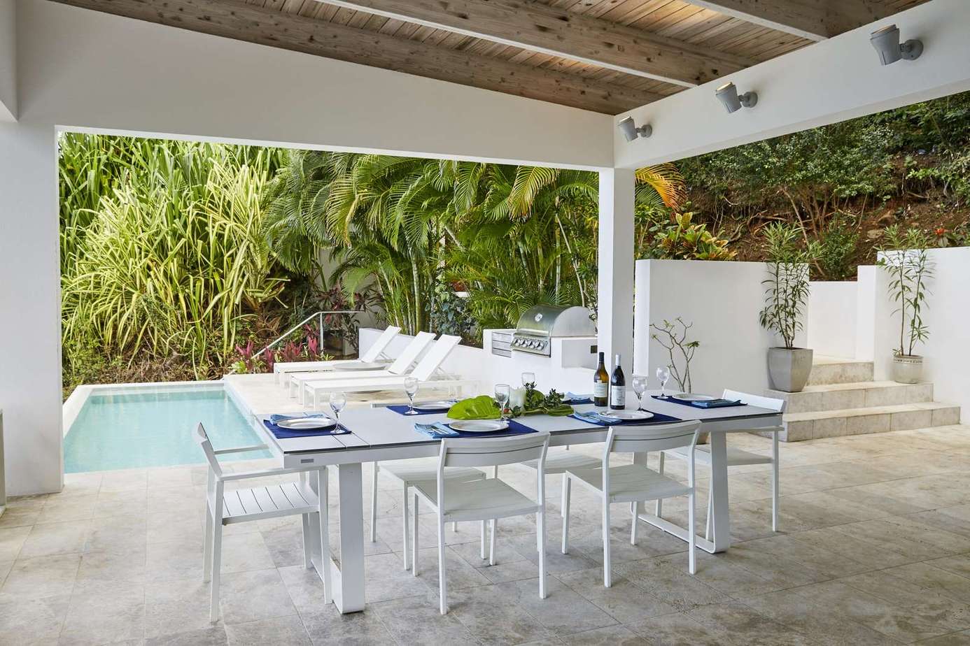 Covered outdoor dining area with pool and lush greenery views